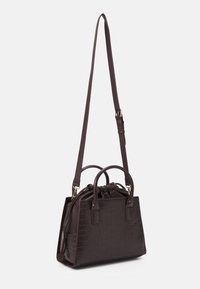 Brun fuskläderhandväska med krokodilstruktur, dubbla handtag och justerbar axelrem. Har en dragkedjestängning och kompakt form.