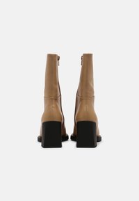 Brązowe skórzane botki za kostkę z wysoką cholewką, kwadratowym słupkiem i zamkiem z tyłu. Gładka faktura i minimalistyczny design.