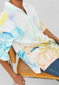 Camicia a maniche corte in tessuto leggero, con un design acquarello multicolore e dettagli blu, gialli e rosa. Colletto con bottoni.