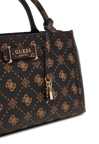 Sac à main synthétique noir avec garnitures dorées, présentant un motif de logos et de motifs floraux, ainsi qu'une tirette de fermeture éclair décorative.