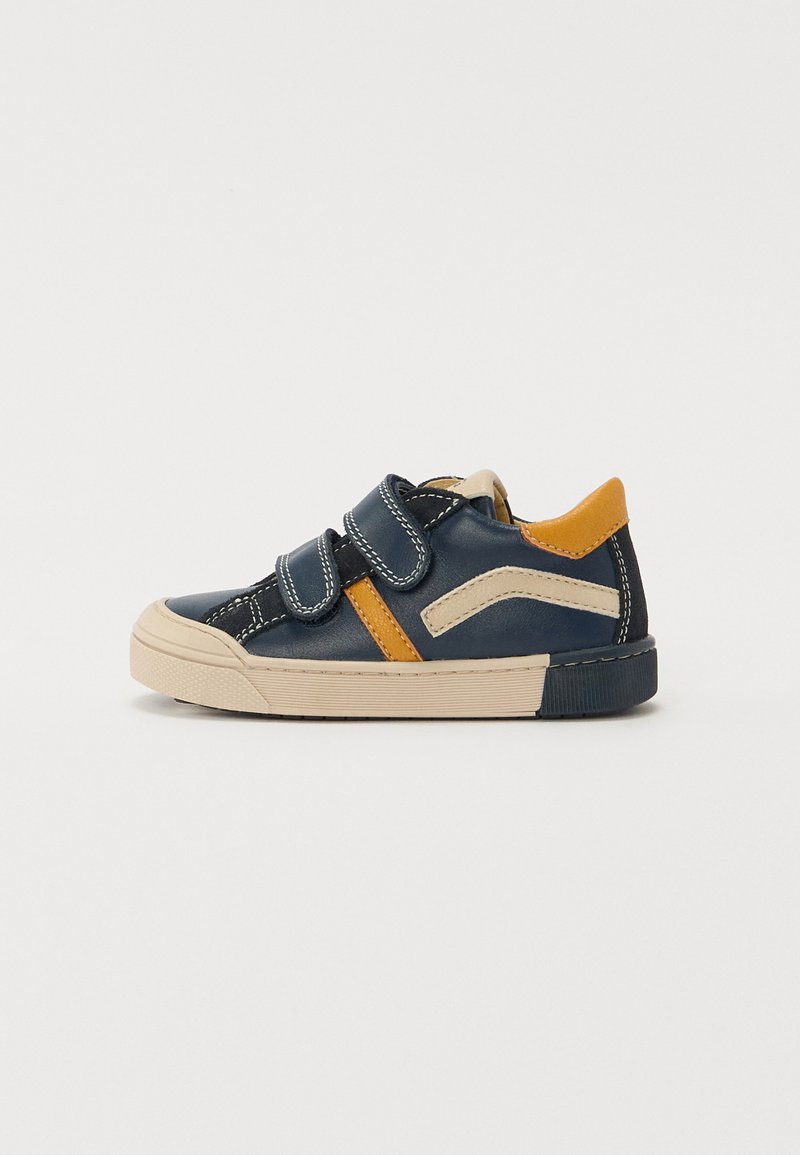 Navy blue leather shoe with two Velcro straps, beige accents, and a textured beige rubber sole. Features orange detailing on the side.
