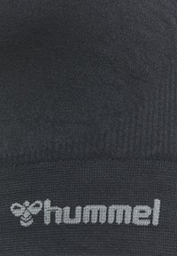 Svart stickad strumpa med ribbat mönster, med "hummel"-logotypen i ljusgrått vid botten. Materialet verkar mjukt och elastiskt.