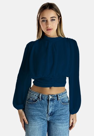 Blouse cropped bleu marine avec de longues manches bouffantes et un col montant ; présente des détails froncés à la taille et une texture de tissu douce.