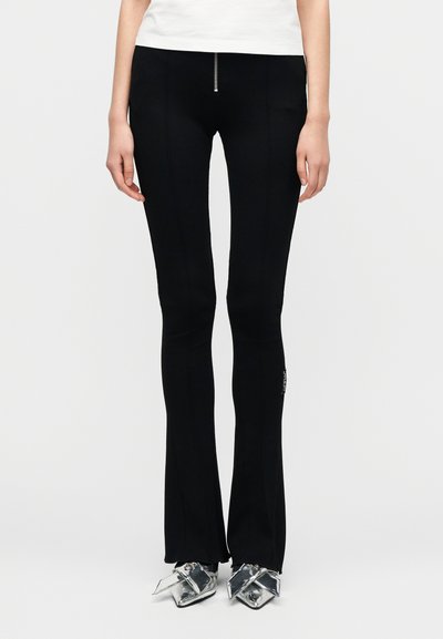 Μαύρο παντελόνι καμπάνα με φερμουάρ στο μπροστινό μέρος, κατασκευασμένο από ελαστικό υλικό. Διαθέτει ραφές στα πλευρά και ετικέτα με λογότυπο στο ύψος του γοφού.