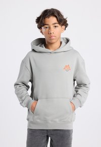Gray hooded sweatshirt with kangaroo pocket, featuring an orange logo on the chest. Ribbed cuffs and hem. Soft texture, relaxed fit.