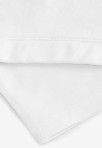 Tissu en coton blanc, présentant deux couches pliées. Caractérisé par une texture lisse et des coutures propres et régulières le long des bords.