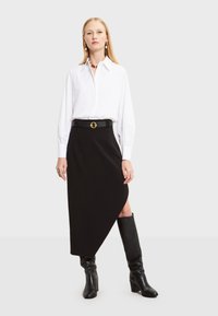 Bijela košulja dugih rukava s pritegnutim manžetama, u paru s visokim crnim asimetričnim suknjama i crnim čizmama do koljena. Akcent s zlatnom kopčom.