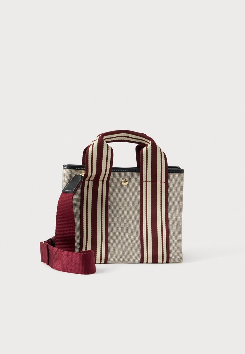 Μικρή μπεζ τσάντα από ύφασμα με φαρδιές κόκκινες και μπεζ ρίγες, με αποσπώμενο κόκκινο λουράκι για τον ώμο, σε λευκό φόντο.