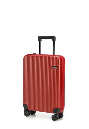 Valise rigide rouge avec des rainures verticales, poignée extensible noire et quatre roues noires pour la mobilité. Présente un logo de marque.
