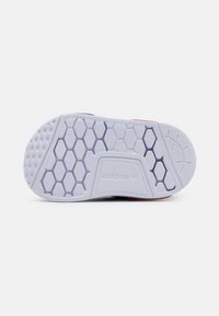 Adidas skosula med en hexagonal texturdesign, främst vit med blå och röda accenter, utformad för grepp och stöd.