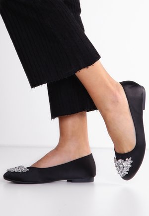 Czarne satynowe baletki z niskim obcasem, ozdobione grupą przezroczystych cyrkonii na palcach. Charakteryzują się gładką teksturą i dopasowanym krojem.