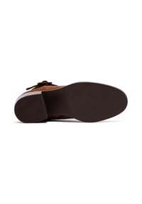 Scarpa in suede marrone con punta arrotondata, dotata di lacci, suola in gomma testurizzata e tacco leggermente rialzato. La parte inferiore presenta un motivo antiscivolo.