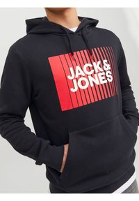 Felpa nera con cappuccio caratterizzata da una grafica rettangolare rossa con linee verticali e il testo "JACK & JONES" in bianco, dotata di una tasca frontale.
