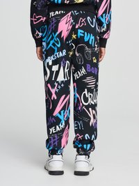 Pantaloni sportivi neri con motivi in stile graffiti colorati in rosa, blu, giallo e bianco. Caviglie elastiche, vestibilità comoda, materiale in cotone.