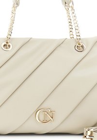 Borsa a tracolla beige trapuntata con cuciture diagonali, hardware dorato e tracolla a catena. Presenta un logo prominente sul fronte. Texture liscia.