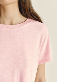 Lichtroze T-shirt met korte mouwen, gemaakt van zachte katoen, met een ronde halslijn en een ontspannen pasvorm, met een subtiel textuurpatroon.