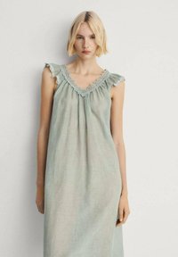 Vestito senza maniche verde chiaro con spalle arricciate, bordo in pizzo attorno al collo e un design morbido e fluido in un tessuto leggero.