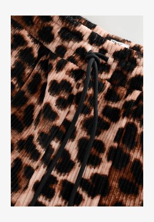 Pantalones tapered de leopardo en suave tejido de pana, con detalle de cordón negro y sutil textura de ribete vertical en tonos de marrón y rosa.