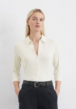 Linen blend, light ivory blouse with a collared neckline and six button placket. Features three-quarter sleeves and smooth texture.