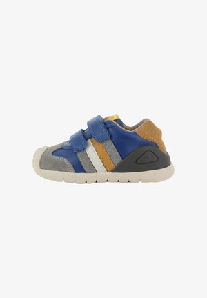 Zapatilla para niños con paneles en azul, gris, amarillo y blanco, dos tiras de Velcro azules, y una suela y parche del talón beige.