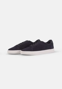 Dark blue suede sneakers with a low profile, white rubber sole, rounded toe, and flat laces, featuring minimalistic design and no visible branding.