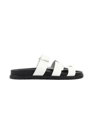 Sandale blanche homme à bout ouvert avec semelle noire et bride ajustable sur fond blanc uni.