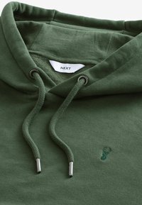 Sudadera verde hecha de tela suave, con un bolsillo canguro, cordones ajustables y un pequeño logo de ciervo bordado.