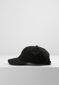 Cappellino da baseball in cotone nero con visiera curva, fori di ventilazione laterali e cinturino regolabile. Presenta un logo sulla parte frontale.