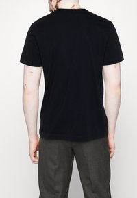 Černé bavlněné tričko s klasickým kulatým výstřihem, krátkými rukávy a hladkým povrchem, zobrazené zezadu.