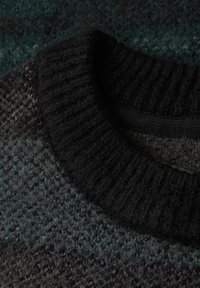 Stickad tröja med en ribbad svart krage; har en texturerad grå kropp med mörkgröna nyanser som smälter in i designen.