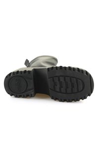 Čierna gumová podrážka s hlbokým zdrsnením, sivý kožený zvršok, výška po členky a bočný zips. Hladká štruktúra, minimalistický dizajn.