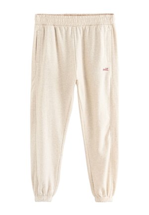 Lysebeige joggingbukser med elastisk talje og manchetter, sidelommer og lille rødt tekst ""self."" på det øverste venstre lår.