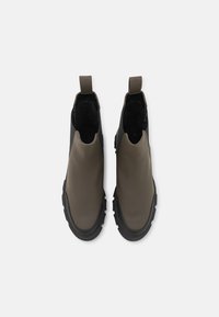 Stivali alla caviglia marroni e neri con finitura liscia, design slip-on, suola in gomma e linguetta sul retro. Pannello laterale testurizzato per una migliore aderenza.