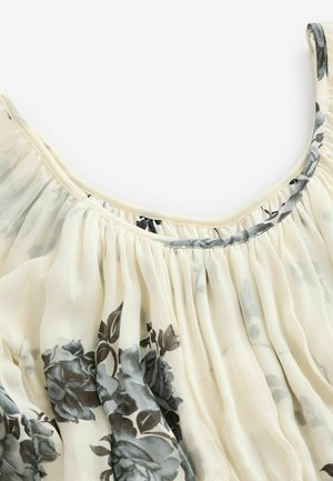 Vloeiende, crèmekleurige blouse met een grijs bloemenpatroon. Zacht, doorzichtig materiaal, geplooid ontwerp en een ronde halslijn met een grijze rand. Lichtgewicht textuur.