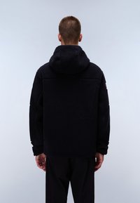 Black fleece jacket with a hood, featuring a textured, plush surface. The back includes a seam across the shoulders and a simple, minimal design.