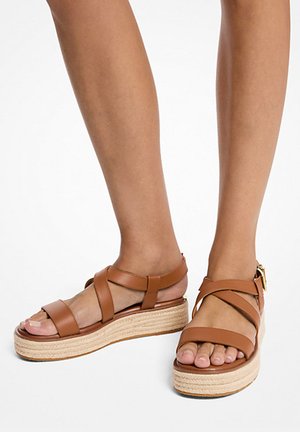 Sandali wedge in pelle marrone con cinturino alla caviglia regolabile, suola in juta intrecciata e tre cinghie incrociate sulla parte superiore del piede.