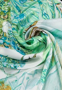 Tissus en satin avec un motif floral dans des teintes de vert et de bleu, avec des textures tourbillonnantes et un drapé fluide, accentué par un doux éclat.