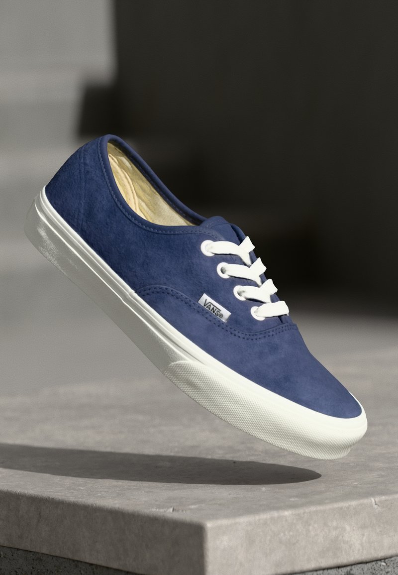 Blauwe suède lage sneaker met witte veters en rubberen zool. Beschikt over een merklabel aan de zijkant en een gladde bovenkant.