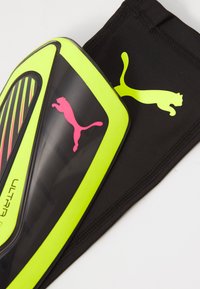 Parastinco Puma con un design nero e verde neon, presenta una superficie strutturata e un logo rosa, accompagnato da una manica nera.