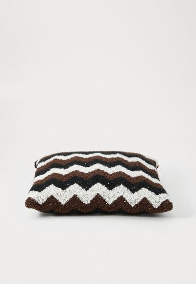 Zigzag-patterned cushion in brown, black, and white, featuring a textured fabric surface and a rectangular shape.
