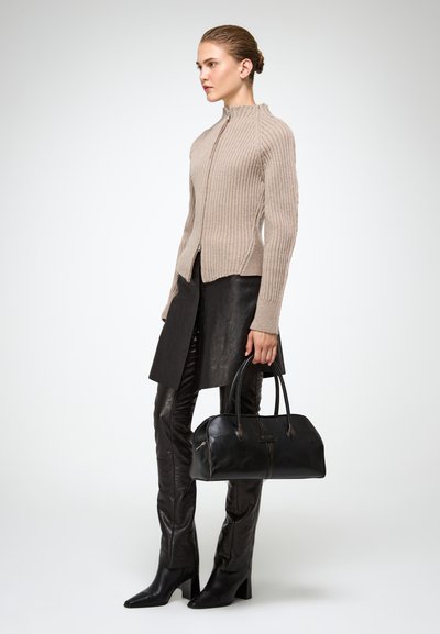 Beige bordázott zipzáras kardigán, fekete bőrszoknya és nadrág, fekete táska strukturált formával és felső fogantyúkkal, magassarkú fekete csizmák.