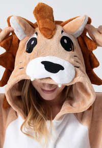 Lion-themed hooded blanket made of soft, plush material. Features a tan body, white face, and 3D ears with a mane, eyes, and fangs.