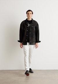 Zwarte denim oversized jas, zwart T-shirt, witte slim-fit jeans en zwarte schoenen met rode accenten. Eenvoudig ontwerp, geen zichtbare patronen.