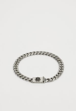 Silver-toned metal chain bracelet with large links, featuring a rectangular clasp engraved with "never forget your roots."