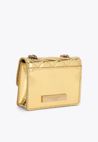 Złota torebka z syntetycznej skóry z pikowanym wzorem, łańcuszkowym paskiem i oznaczeniem marki. Kompaktowy, prostokątny kształt z błyszczącym wykończeniem.