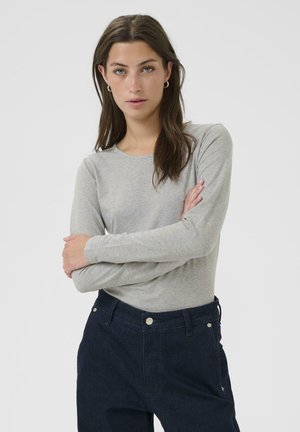 Gray long-sleeve top with a round neckline, crafted from soft fabric, paired with dark denim pants featuring a classic fit and pockets.