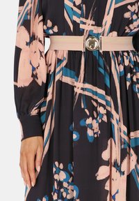 Sukienka w kwiatowy wzór w ciemnym granacie z różowymi i turkusowymi akcentami, z długimi rękawami i beżowym paskiem z metalową klamrą.