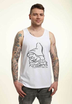 Hvid tanktop med et sort grafisk motiv af en smilende gnom og ordet "HAPPY", iført med grå jeans, og farverige tatoveringer på armene.