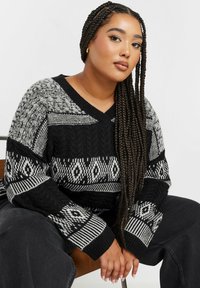 Schwarzer und grauer gestrickter Pullover mit V-Ausschnitt, der komplizierte Muster wie Rauten und Streifen sowie gerippte Bündchen aufweist.