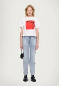 White cotton t-shirt featuring a red square graphic with "MAX & Co." in black, paired with light blue denim jeans and black chunky shoes.
